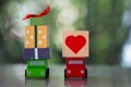 Toy car delivering heart and gift box for Valentine`s day on blur of nature background Royalty Free Stock Photo