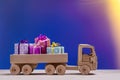 Toy car with gifts in boxes on festive background.