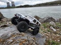 Toy car Jeep Wrangler on stones by the lake with a view of nuclear power plant