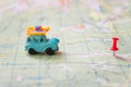 A toy car with a load travels to its destination by a designated red pin. Geographical concept of travel and leisure. An old blue Royalty Free Stock Photo