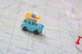 A toy car with a load travels to its destination by a designated red pin. An old blue trailer moves along a map to a red pushpin Royalty Free Stock Photo