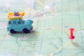 Toy car with a load travels to its destination by a designated red pin. An old blue trailer moves along a map to a red pushpin. Royalty Free Stock Photo