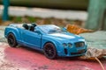 Toy car model Bentley Continental 2010. Blue color. Side view. On the leaves of fallen leaves. Close-up.