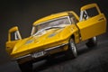 Toy car model Corvette Sting Ray 1963 year. Yellow color. Front view. Open doors. Close-up. Macro. Royalty Free Stock Photo