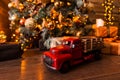 Toy car with a red body is on a wooden floor under the Christmas tree with gifts Royalty Free Stock Photo