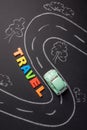 Toy car on the road and inscription plastic letters travel on ch