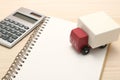 Toy car trucks, a notebook, and a calculator on wood.