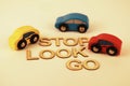 Toy cars next to the words stop, look and go