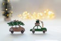 Toy cars on a white background. A green wooden car with New Year's gifts on the roof and a beige car with a Christmas tree.