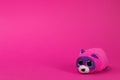 Toy cartoon pink and purple mouse sits on a pink background