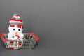 A toy Christmas Snowman is in a metal shopping basket from the supermarket on a grey background. New year`s shopping concept Royalty Free Stock Photo