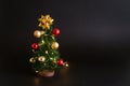 Toy christmas tree with balls on a black background with a garland. Cute