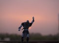 A toy clothed as a powerful super human in the backdrop of setting sun.