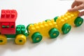 Toy color designer, train. the child plays and builds out of cubes. hands of the kid. on a white background