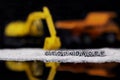 Toy construction vehicles and sand with the word groundwork on beads reflected