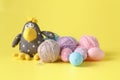 Toy crow on yellow background with wool clew