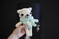 A toy on a dark black background in the hands of an unrecognizable young woman. Crocheted white cat in a mint Royalty Free Stock Photo