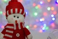 Toy decorative Christmas snowman on a background of lights in a red hat and scarf Royalty Free Stock Photo