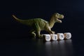 Toy dinosaur that looks like a Tyrannosaurus, Velociraptor, Allosaurus, Megalosaurus or Plateosaurus stands against a dark