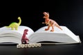 Toy dinosaurs next to an open book and cubes with the inscription history. Concept of studying history, the Mesozoic era and