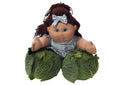 Toy doll leaning on two cabbages