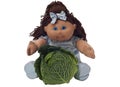 Toy doll sitting behind a cabbage Royalty Free Stock Photo