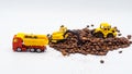 A toy excavator loads coffee beans into the back of a toy truck with a bucket, and a toy bulldozer rakes roasted coffee beans into Royalty Free Stock Photo