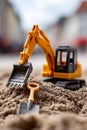 A toy excavator and shovel in the sand with a house in the background Royalty Free Stock Photo