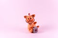 Toy figure of a pig in the image of a doctor on a pink background. Close up. Selective focus