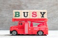 Toy fire ladder truck hold block in word busy on wood background