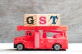 Toy fire ladder truck hold block in word GST Abbreviation of Goods and Services Tax on wood background Royalty Free Stock Photo