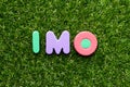 Toy letter in word IMO Abbreviation of in my opinion on green grass background