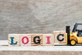 Toy forklift hold block c to complete word logic on wood background