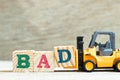 Toy forklift hold block d to complete word bad on wood background Royalty Free Stock Photo