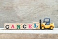 Toy forklift hold block L to complete word cancel on wood background