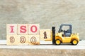 Toy forklift hold block 1 to complete word ISO9001 on wood background