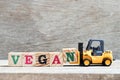 Toy forklift hold lette block n to complete word vegan on wood background Royalty Free Stock Photo