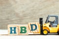 Toy forklift hold block D to complete word HBD Abbreviation of happy birthday on wood background