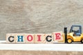 Toy forklift hold block e to complete word choice on wood background