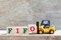 Toy forklift hold letter block o to complete word FIFO Abbreviation of first in first out