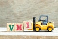 Toy forklift hold block I to complete word VMI abbreviation of vendor managed inventory on wood background Royalty Free Stock Photo
