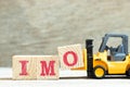 Toy forklift hold block o to complete word IMO Abbreviation of in my opinion on wood background Royalty Free Stock Photo