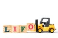 Toy forklift hold letter block o to word LIFO Abbreviation of last in first out on white background