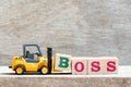 Toy forklift hold block s to complete word boss on wood background