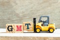 Toy forklift hold block T to complete word GMT abbreviation of Greenwich Mean Time on wood background