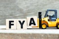 Toy forklift hold block A to complete word FYA Abbreviation of For your action or attention on wood background