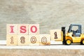 Toy forklift hold block 1 to complete word iso 18001 on wood background