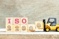 Toy forklift hold block 0 to complete word iso 22000 on wood background