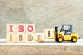 Toy forklift hold block 1 to complete word iso 18001 on wood background