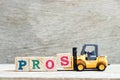 Toy forklift hold block to complete word pros on wood background Royalty Free Stock Photo